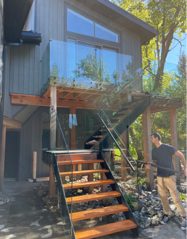 Jackson Elliott cleaning some glass railings at a house in Blue Mountain