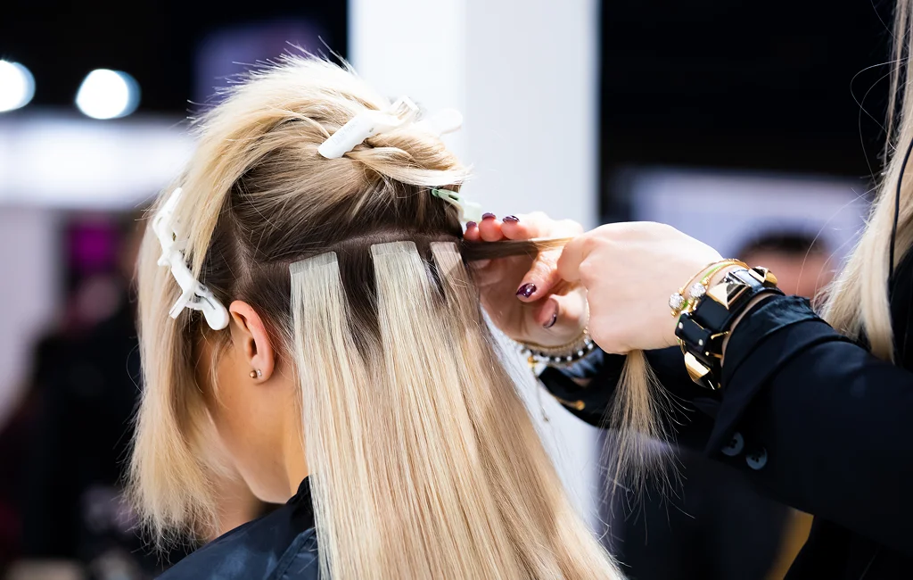 A stylist installs hair extensions in Vero Beach, FL on a client.

