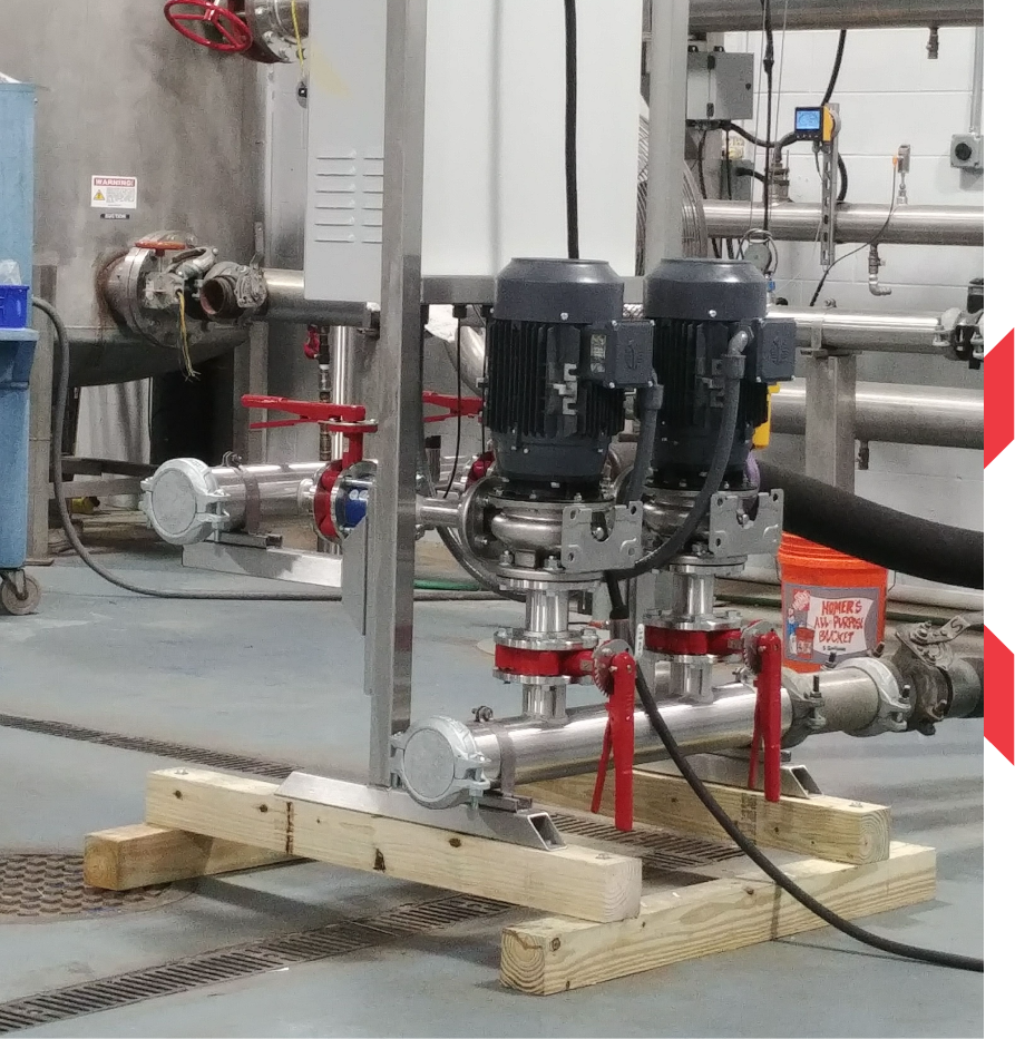 A plumbing manufacturer's representative demonstrating a pump control panel to contractors inside a mechanical room.