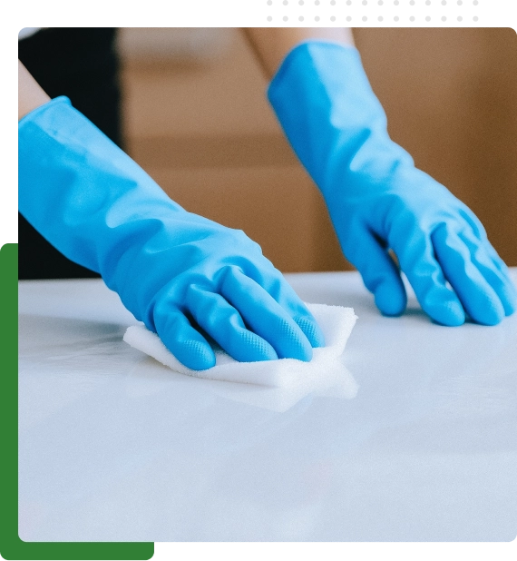 Staff member applying sanitization services to high-touch surfaces in a meeting room.