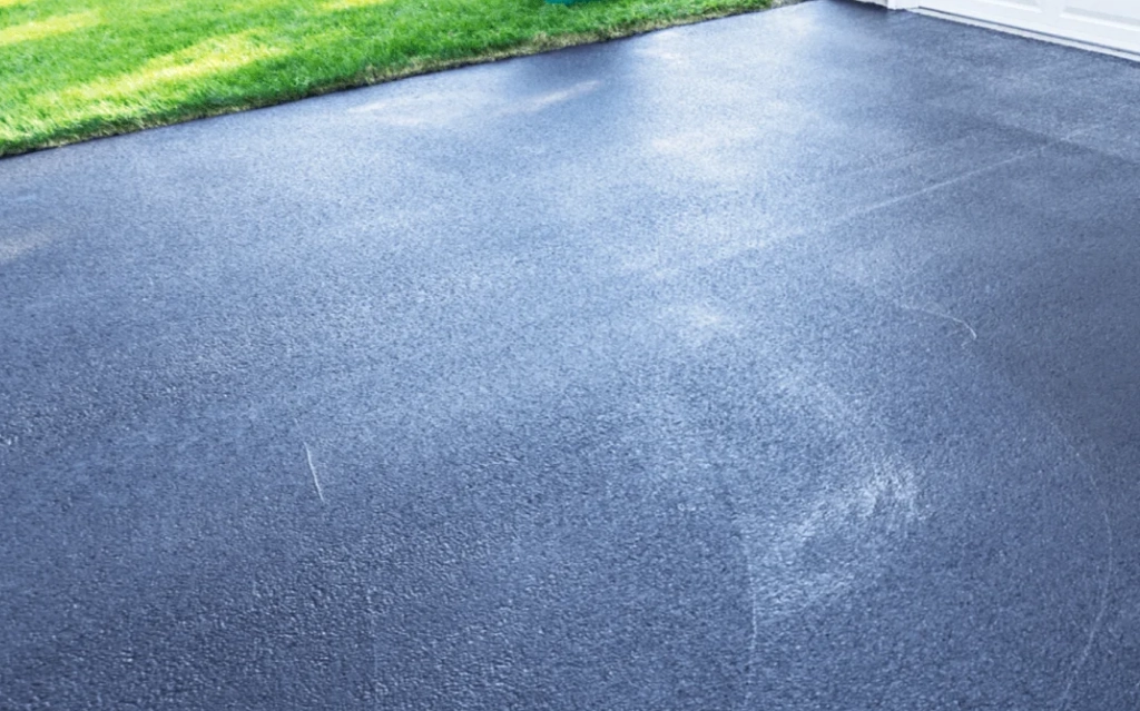 Technician performing driveway pressure wash in Edmonton on a residential concrete surface.