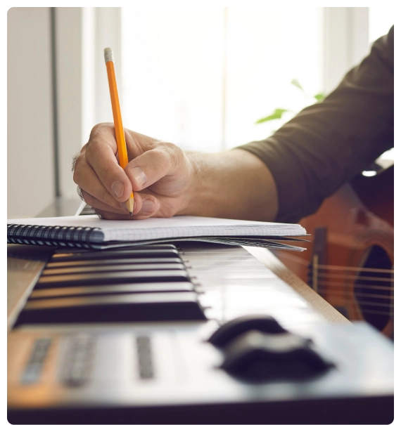 A songwriter composing at a keyboard during a songwriting education in New York program.