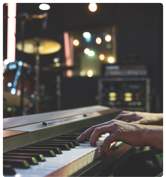 A performer taking a bow after live piano and keyboard performances in an intimate recital space.