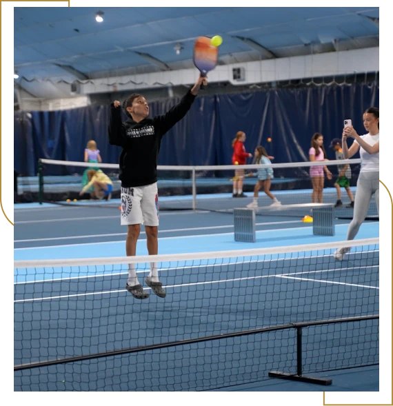 A group of children enjoying a tennis academy for kids lesson with a coach in Burlington.