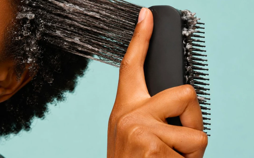 Stylist applying detangling spray to reduce knots and improve manageability.