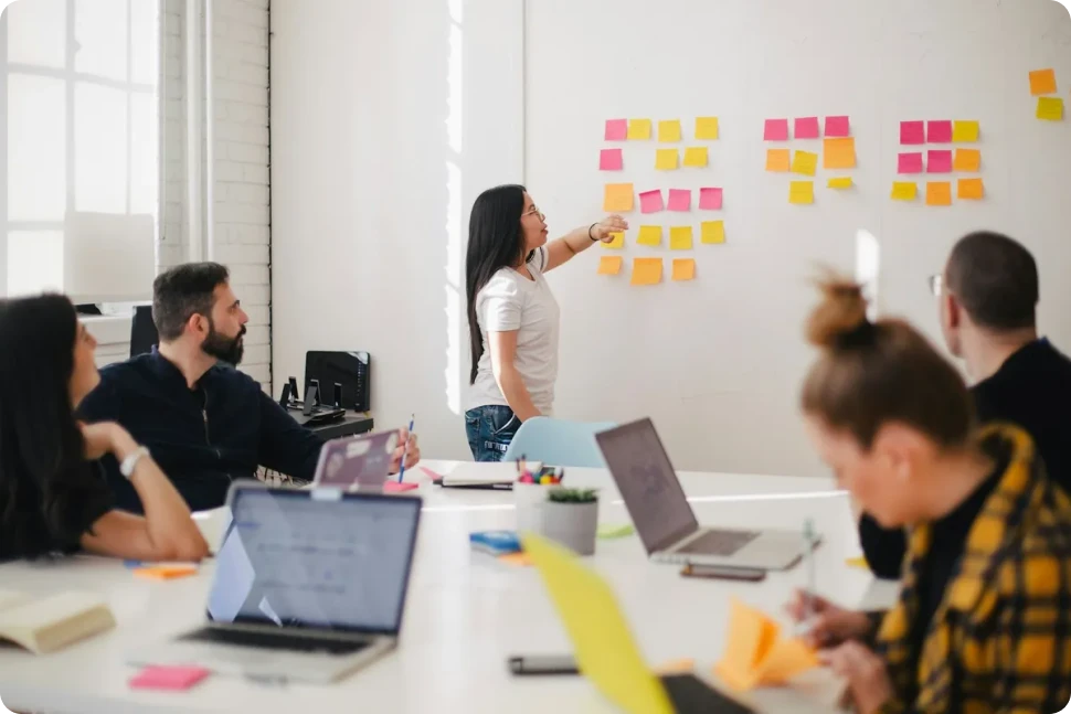 A team planning session around a wall of sticky notes in a bright meeting room